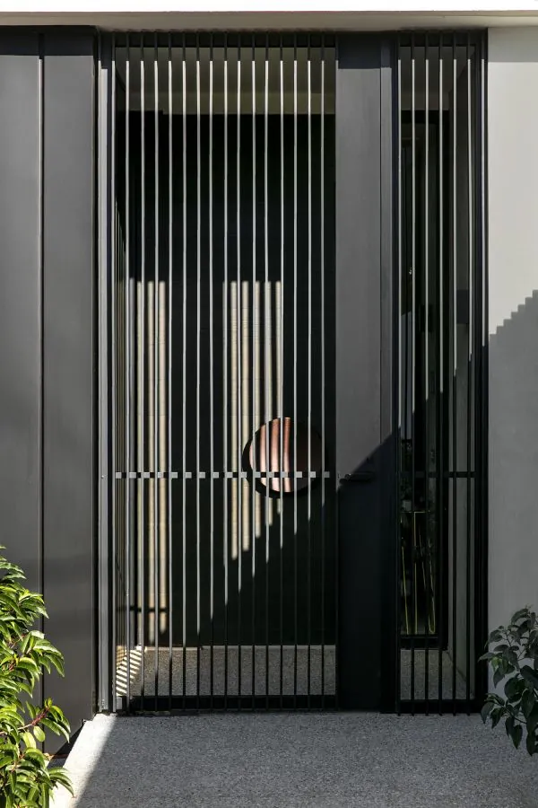 Acceso negro de barrotes verticales, ejemplo de herrería moderna para casas